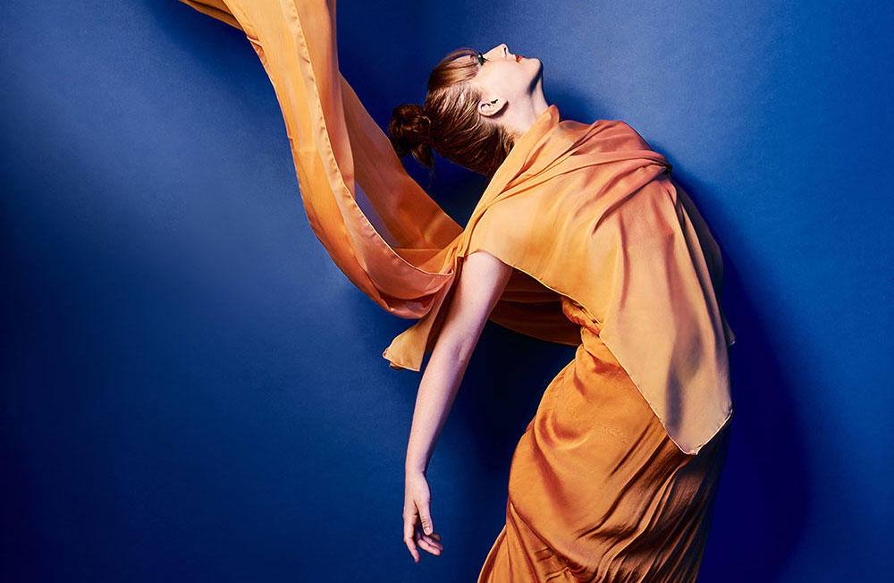 dancer in orange filmy dress on royal blue background