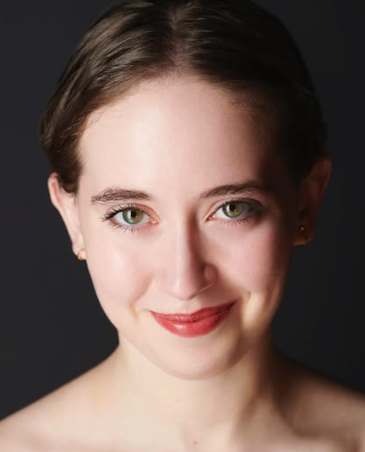 head and shoulders photo of young white woman looking at camera with brown hair tied back and wearing red lipstick