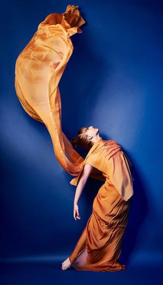 Dancer draped in sweeping gold fabric.